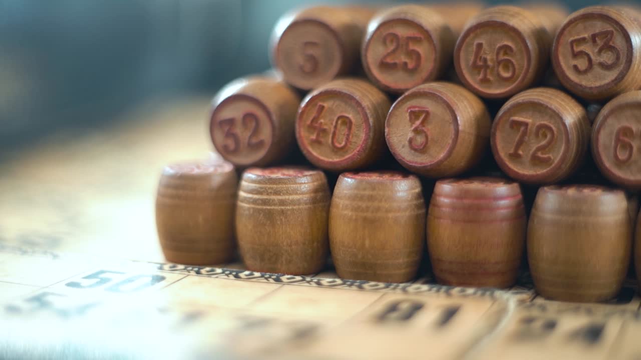 increíble creativo suave soñador macro tiro de bingo barriles de madera en una fila, figuras de madera, viejos números de fondo, juego de mesa vintage, cámara lenta 120 fps video de gimbal comercial, movimiento de grúa