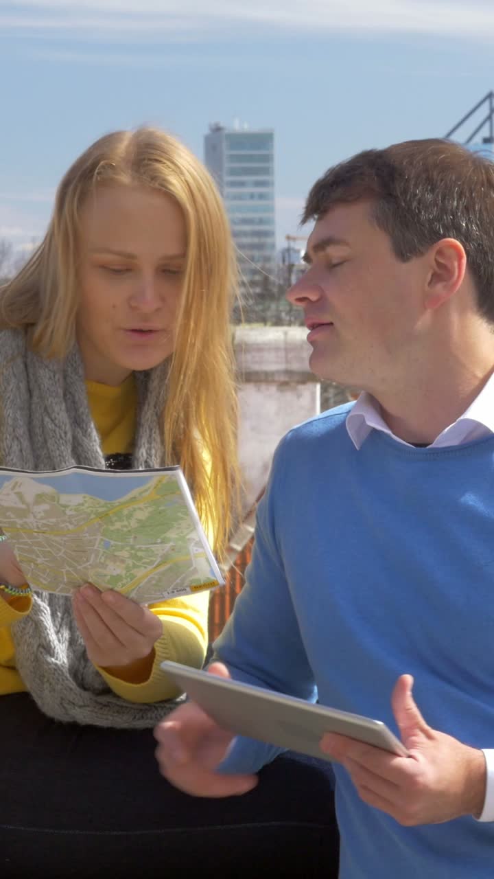 People looking at a map with city buildings in the background
