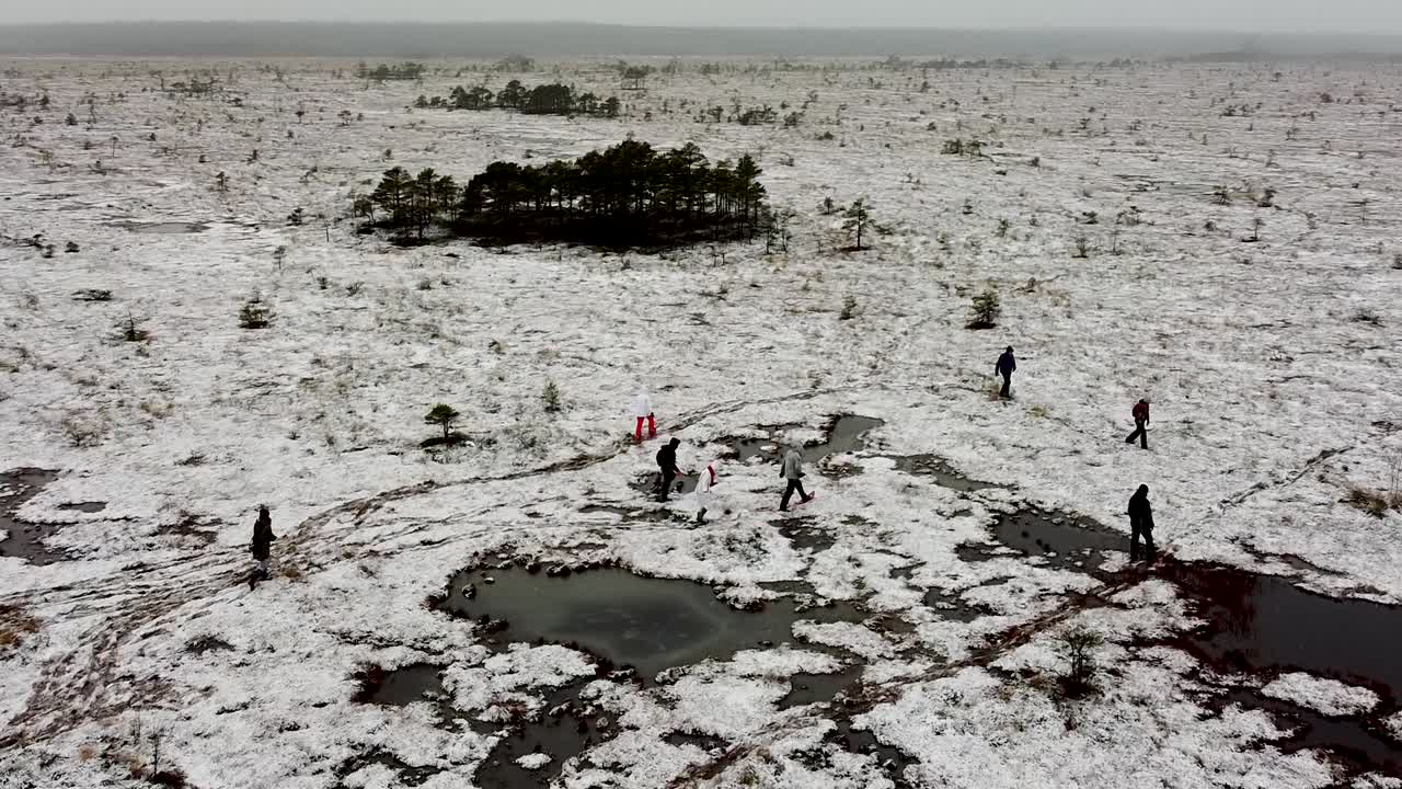 에스토니아의 수마아 발게라바에 있는 얼어붙은 늪지 풍경을 걷는 사람들의 공중 드론 보기