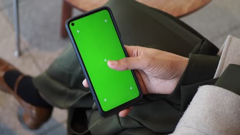 woman holding a smartphone with a green screen