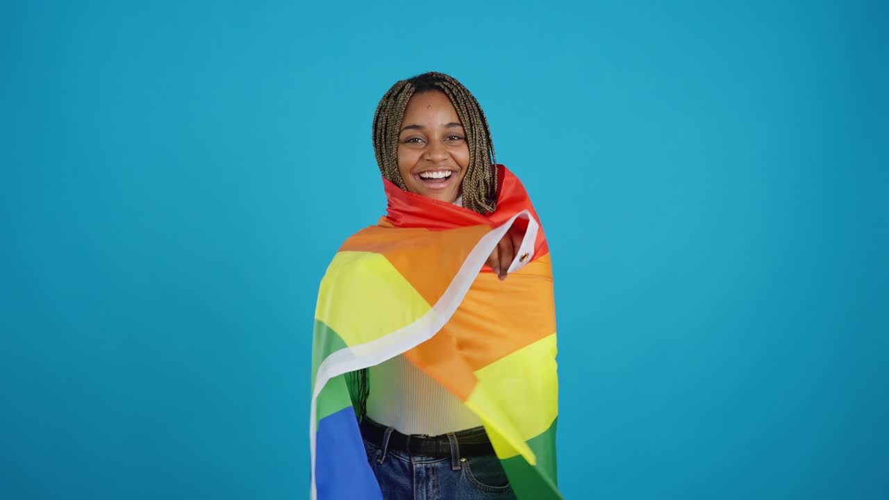 Giovane donna nera sorridente con bandiera arcobaleno del Pride