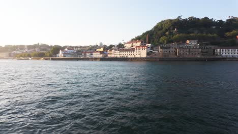 vila nova de gaia riverside with scenic buildings and lush hills by the douro river at golden hour