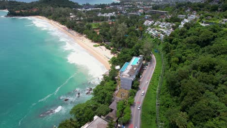 Aerial drone view of a hotel resort at Phuket, Thailand with the turquoise ocean waves crashing against the rocks facing the infinity pool at Surin beach in 2025