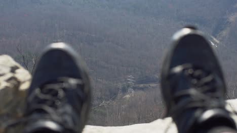 A-person-dangles-their-feet-over-a-cliff-at-pretty-place-chapel