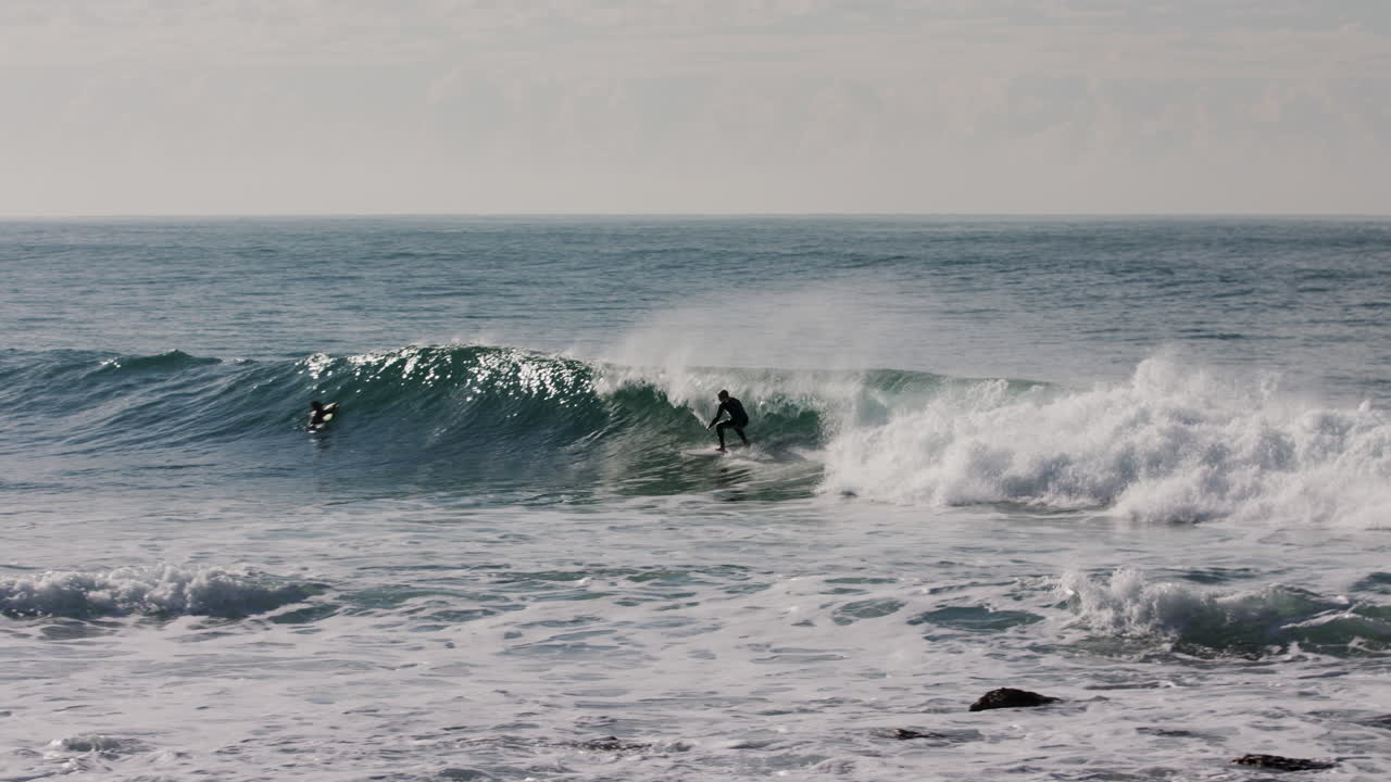 Mustapukuinen surffaaja nappaa pienen aallon Australian rannikon edustalla lähellä Bondi Beachia.