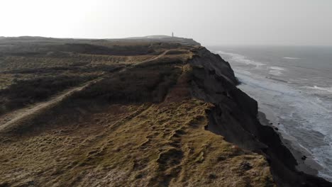 Aerial-view-of-the-Lighthouse-and-steep-slopes-at-Rubjerg-Knude-by-the-North-Sea,-Denmark