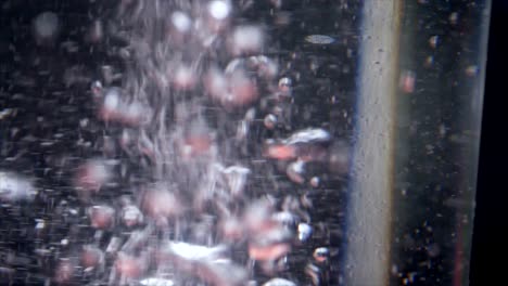 Macro-shot-of-water-bubbles-raising-up-in-a-glass-of-water-against-dark-background-Close-up-top-view