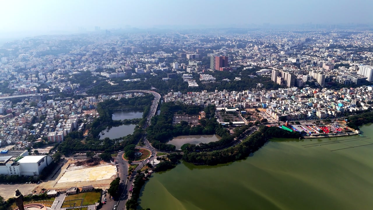 Wide aerial shot of Hyderabad showcasing urban density, lakes, parks, and landmark structures blending into a vast metropolitan skyline. world's largest, 125-foot-tall DR. B. R. Ambedkar statue.