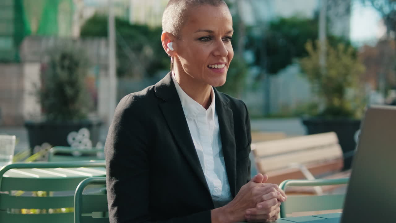 Smiling Businesswoman on a Video Call at an Outdoor Cafe