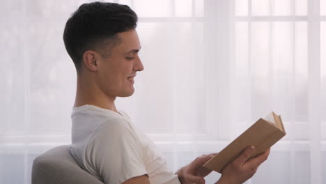 man reading a book by the window