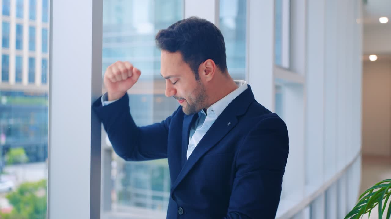 Thoughtful, sad businessman punches window frame in desperation and disbelief after learning he lost funds over major business mistakes