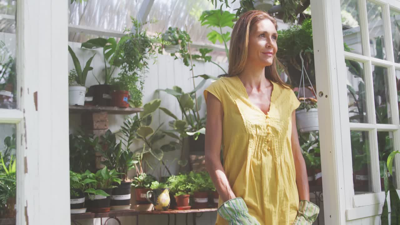여성이 미소 짓고 온실에서 카메라를 보고 있습니다.