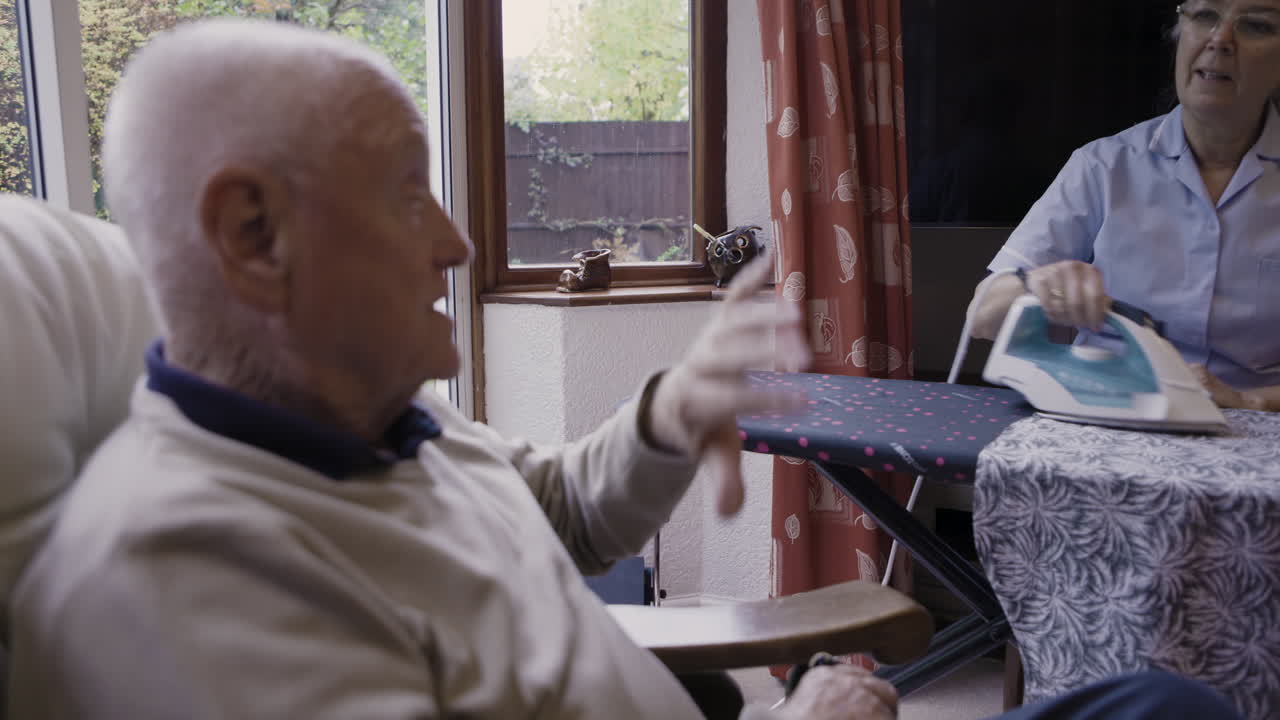 Woman ironing for an elderly man