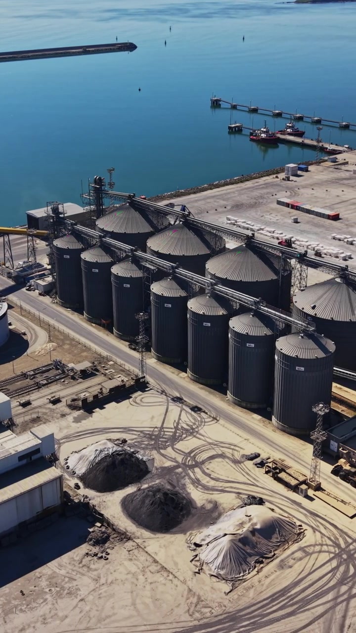 Área industrial portuária com navios e tanques de armazenamento.