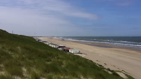 a net row of white beachside cabins on a white sandy beach in wijk an zee, netherlands