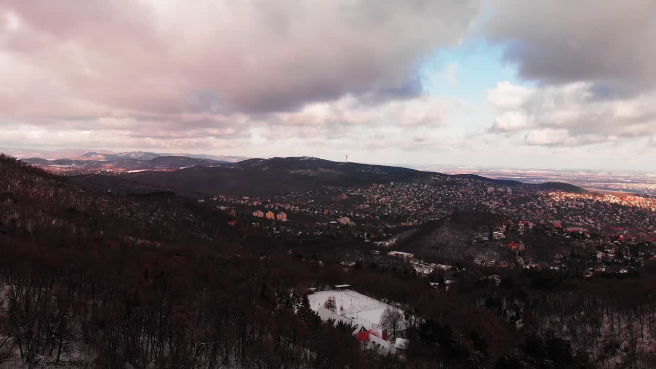 Winter aerial footage on a scenery landscape with a city between the snowy hills in Europe