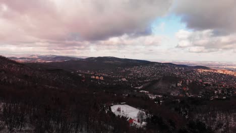 winter aerial footage on a scenery landscape with a city between the snowy hills in europe