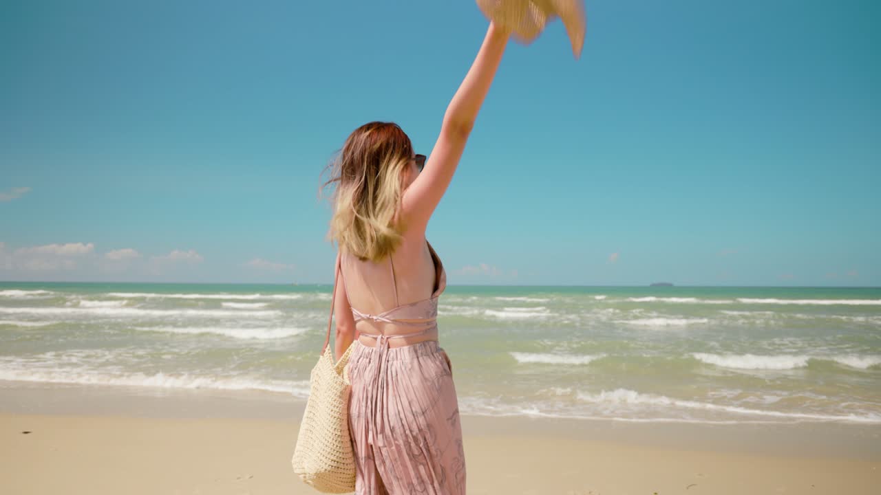 슬로우 모션 : 젊은 여성이 선글라스를 착용하고, 열대 국가에서 휴가를 즐기며 미소 짓고, 아시아의 아름다운 여성이 여름날 해변에서 즐겁게 고 춤을 춘다.