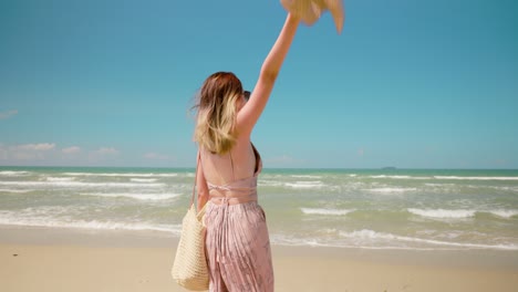 slow motion shot. young female wearing sunglasses, smiling having fun on vacation in tropical country. asian beautiful woman walking and dance with joy in the beach on a summer day
