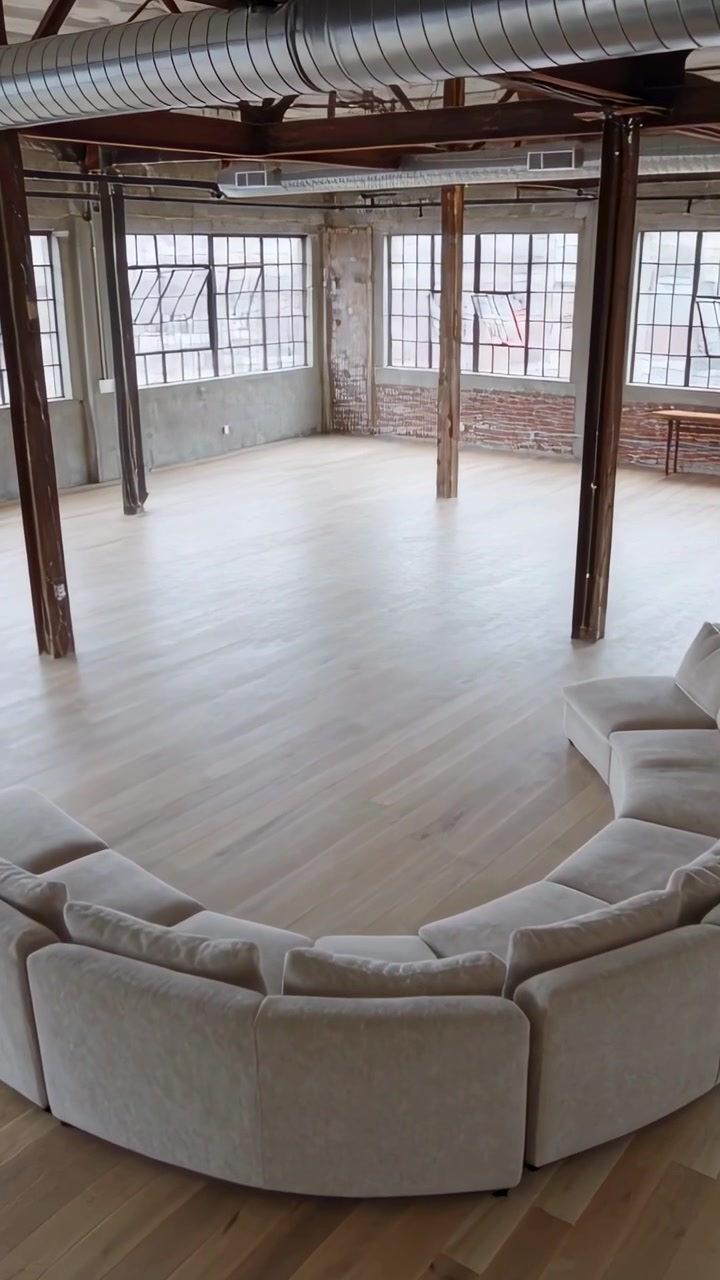 Video verticale: La telecamera inizia una panoramica, rivelando un divano componibile curvo in un loft, mettendo in mostra lo spazio.