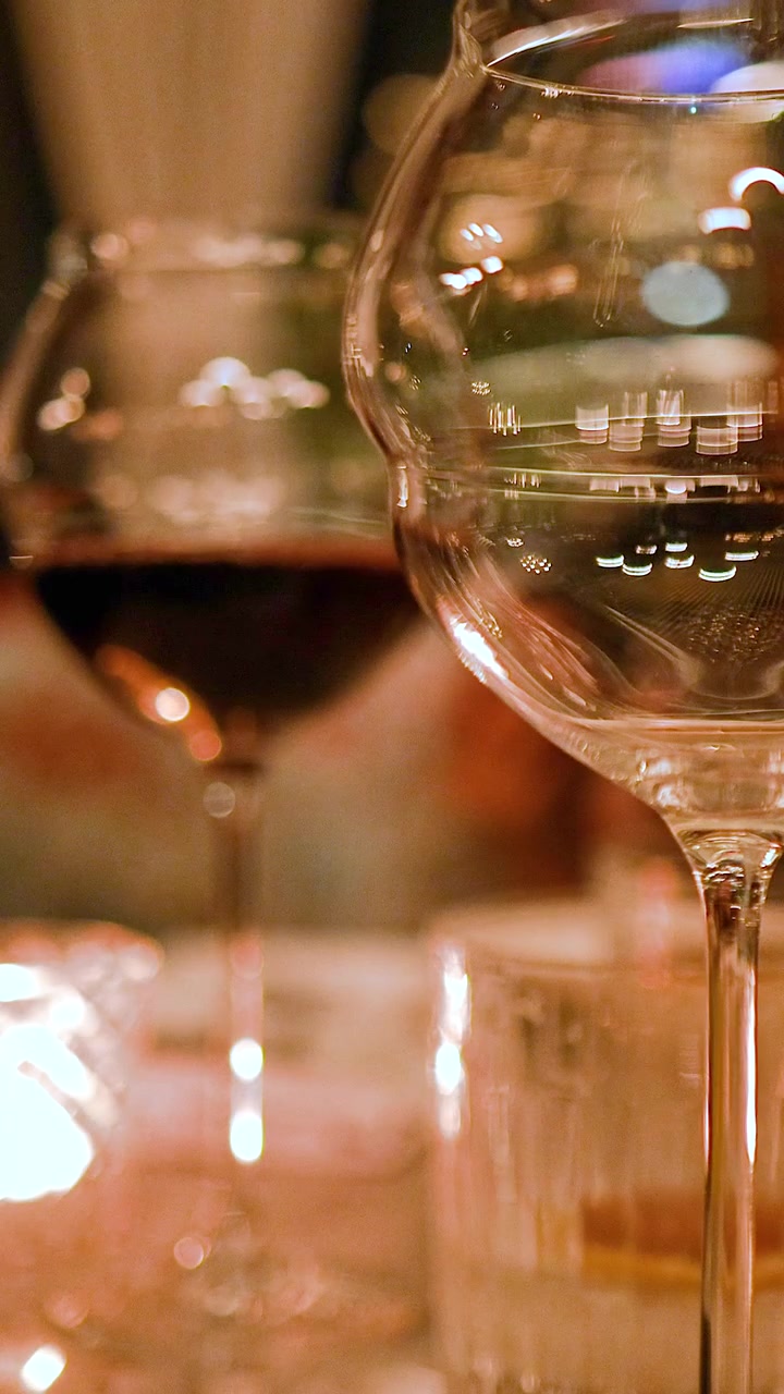 Un calice si riempie di vino rosso in un'atmosfera calda e a lume di candela, evidenziando eleganza e raffinatezza.