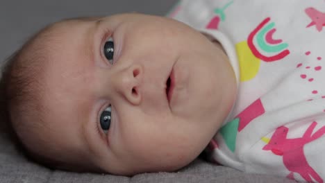 Extreme-close-up-of-baby-girl-looking-at-camera,-wiggling,-making-facial-expressions