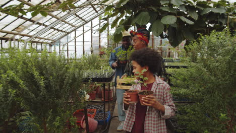 african american family carrying plants through greenhouse