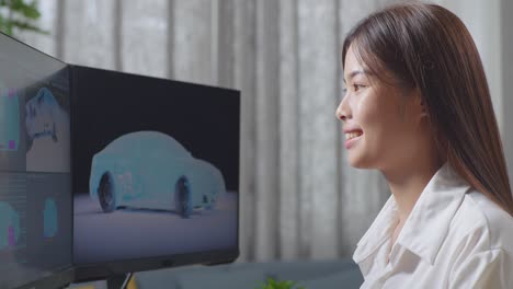 아시아 여성 자동차 디자이너가 스튜디오의 데스크 컴퓨터에서 ev 자동차의 3d 모델을 작업하는 가까운 측면 뷰