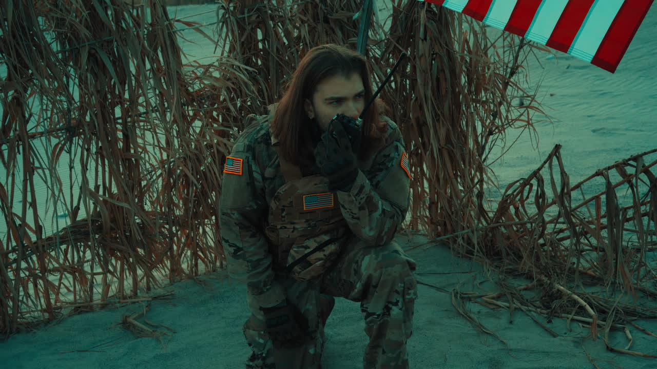 A soldier in an abandoned desert speaks into the radio to call for help