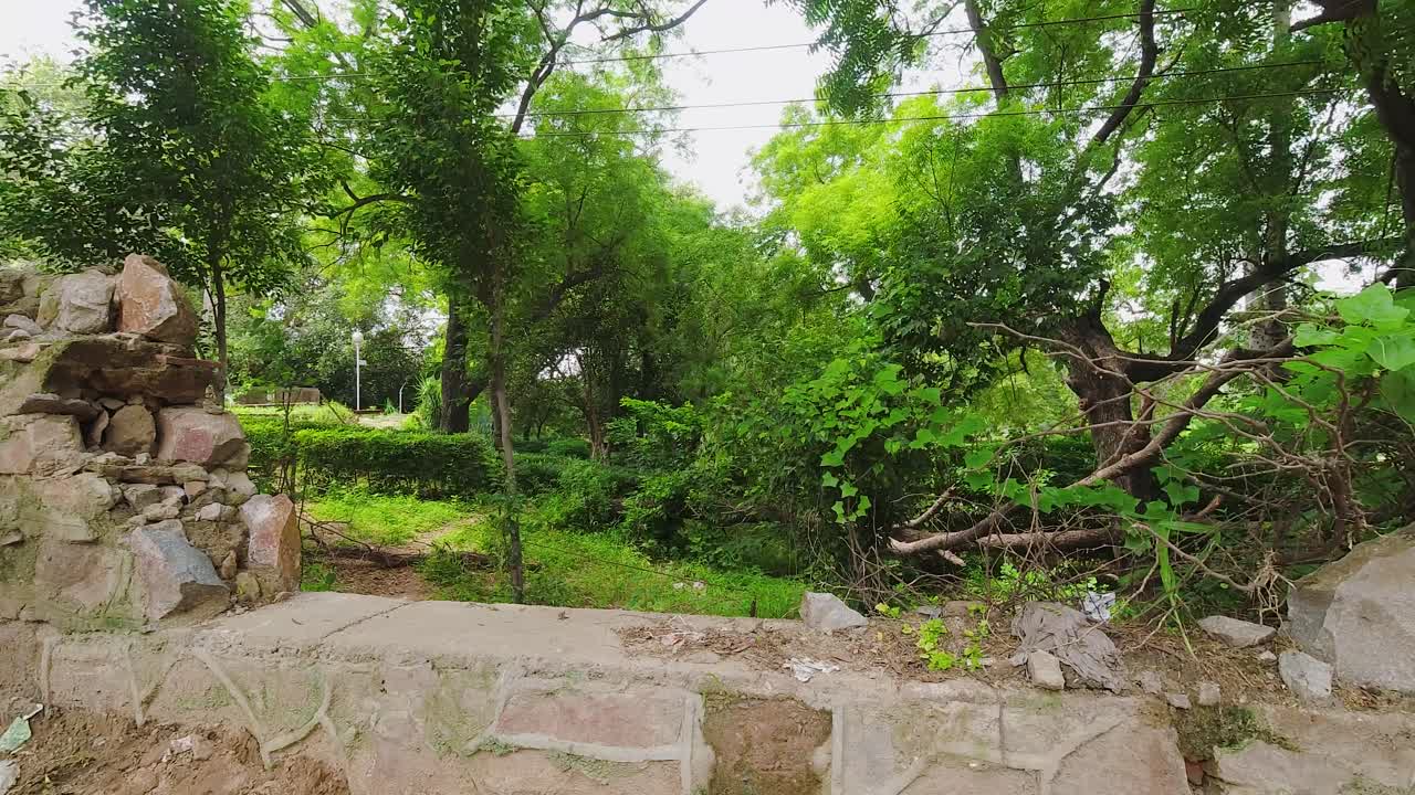 una pared rota fuera del hito qutab minar en nueva delhi con árboles verdes