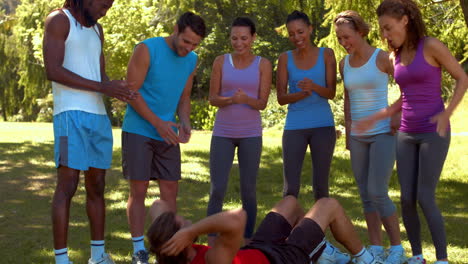 en formato de alta calidad grupo de fitness animando al hombre haciendo abdominales