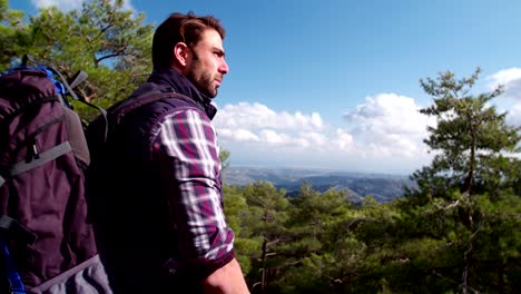 male hiker standing on mountain peak looking at the view