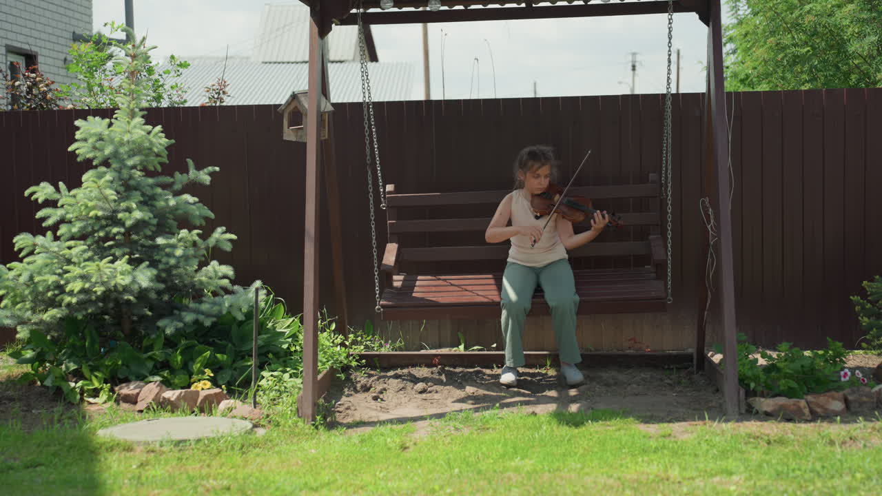White Girl Focuses On Playing Music Outdoors, Teenage Girl With Violin Enjoys Sunny Day In Garden Setting, Young Girl With White Hair Carefully Practices Her Melodies On Sunny Backyard Bench