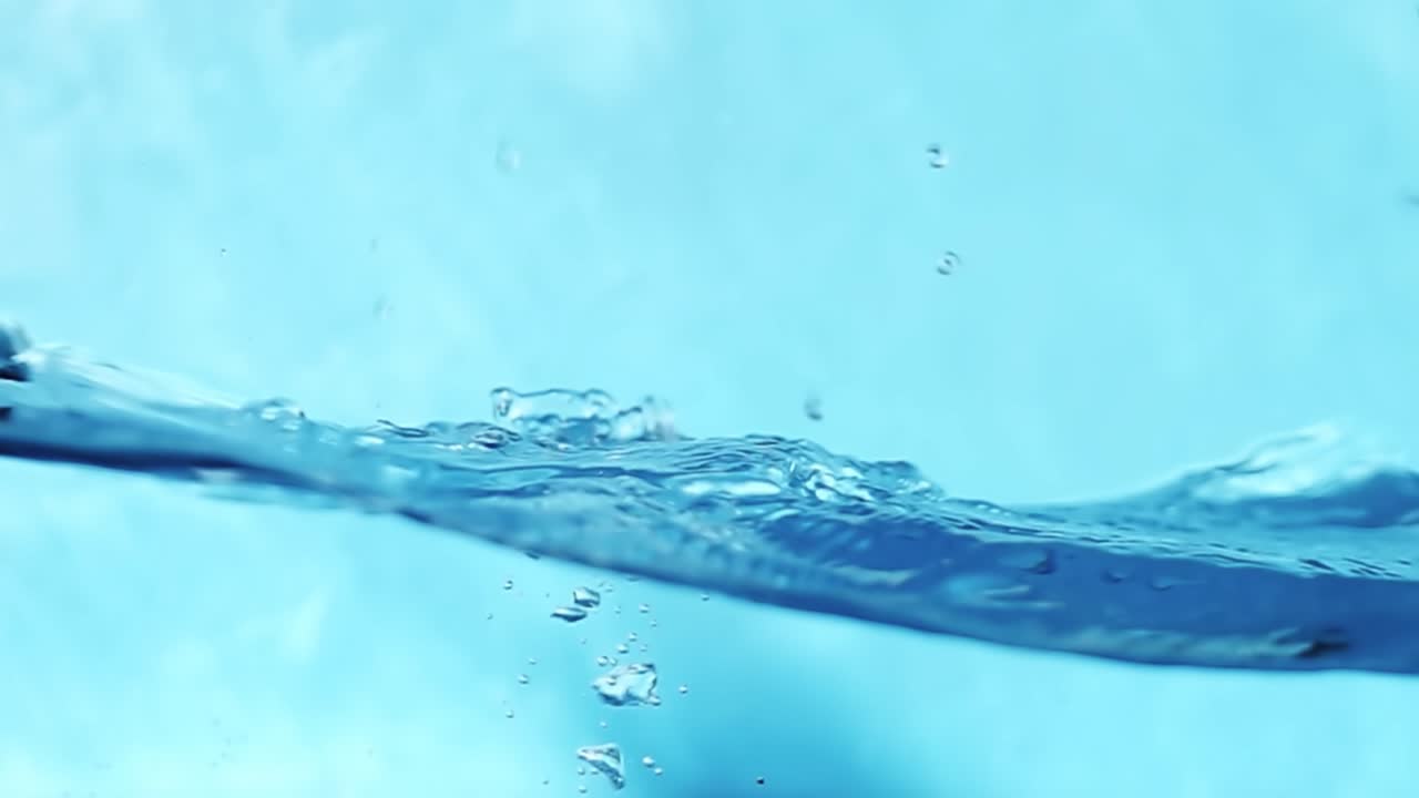 파란색 배경에 물방울이 어지고 떨어지는 물결, 스튜디오 촬영, 느린 동작 4k 원시 비디오.