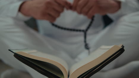 muslim man in prayer with quran and rosary