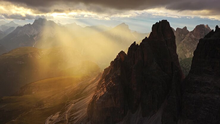 Paesaggio idilliaco delle Dolomiti italiane, ripresa con drone dei raggi solari che filtrano tra le nuvole illuminando le vette delle Tre Cime di Lavaredo