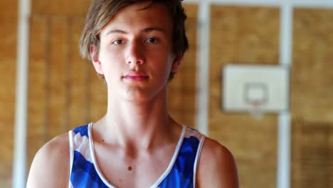 porträt eines schuljungen, der auf dem basketballplatz steht