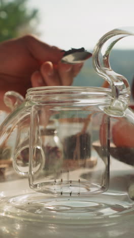 el marido vierte la mezcla de té seco en la tetera. el novio cariñoso hace té para la familia amada para el desayuno en vacaciones. accesorios de té para la ceremonia