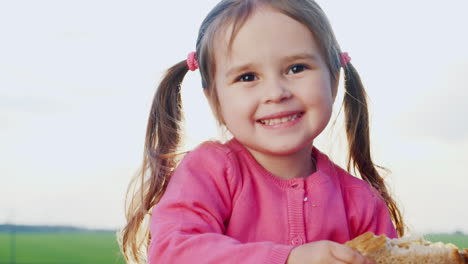 funny three years girl eating a sandwich in the sun outdoors