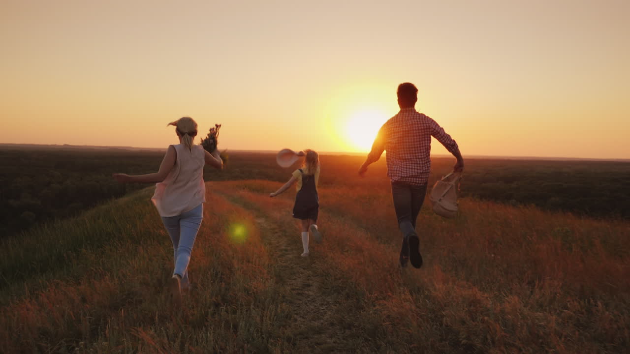 una familia alegre corre alegremente hacia el sol agitando emocionalmente mochilas y un ramo de flores