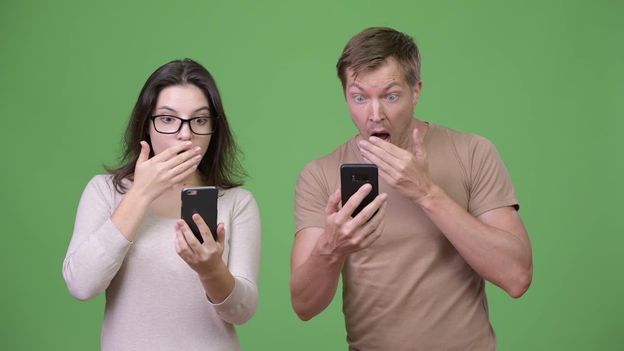 Young couple using phone and looking shocked together