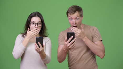 young couple using phone and looking shocked together