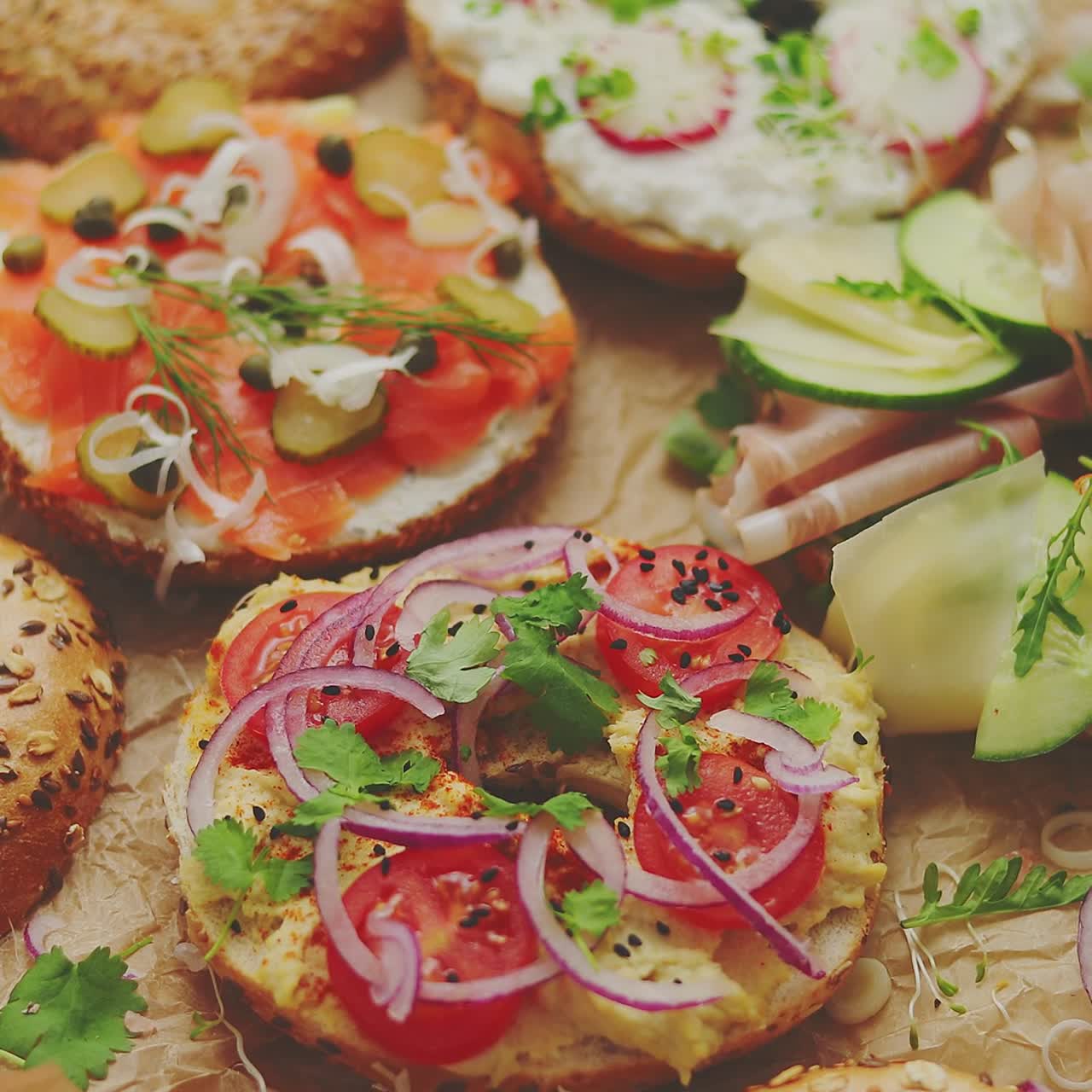 sándwiches de bagel con varios aderezos, salmón, requesón, hummus, jamón, rábano y hierbas frescas.