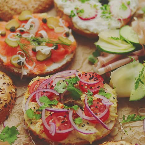 bagel sandwiches with various toppings  salmon  cottage cheese  hummus  ham  radish and fresh herbs