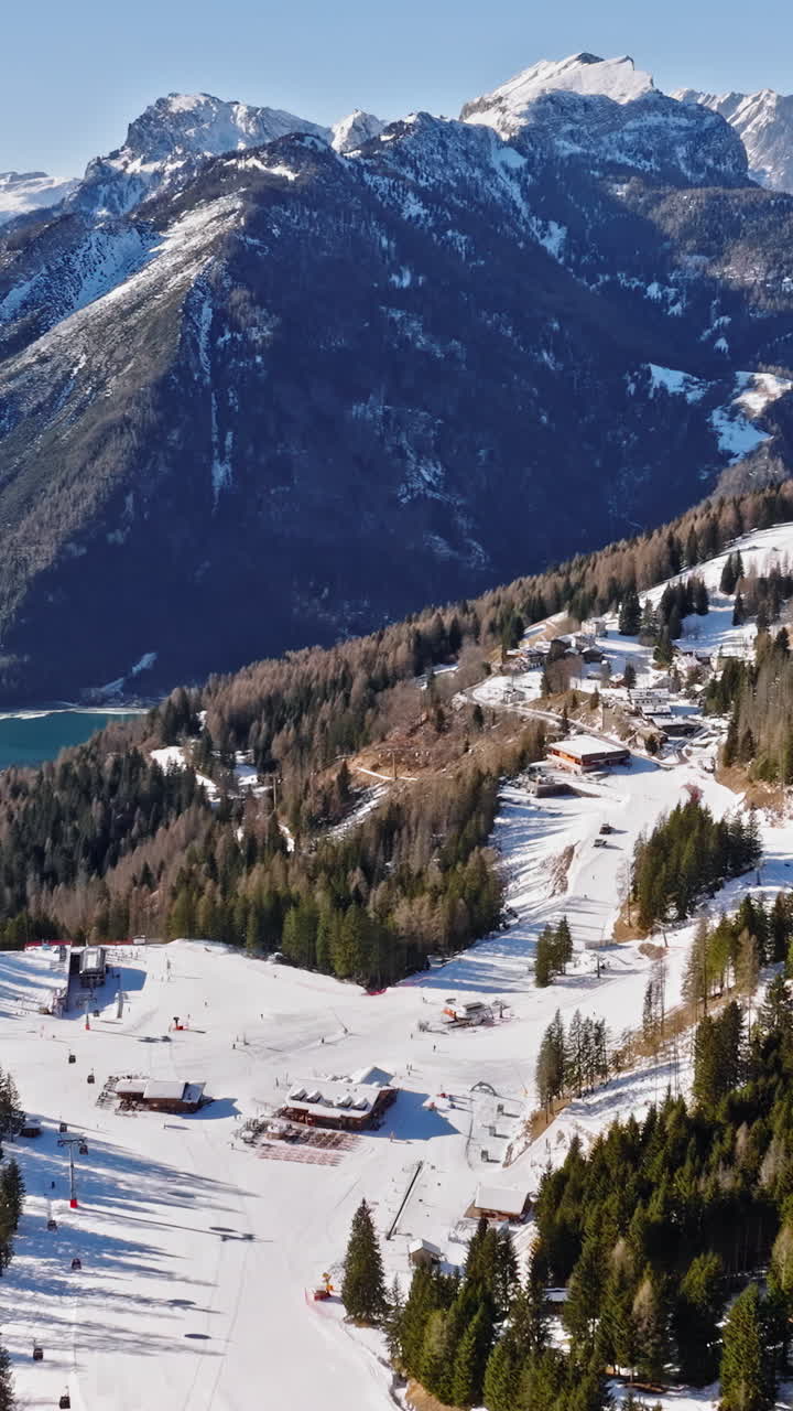 Aerial drone view of the Alleghe village with Lake Alleghe, in the province of Belluno, Dolomites, Italy. Vertical
