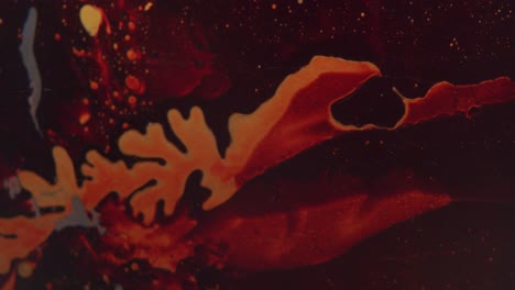 black liquid forming abstract forms looking like blood vessels on a red surface