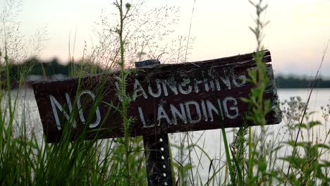No-Launching,-No-Landing-Signboard-On-The-Bank-Of-Lake-At-Sunset