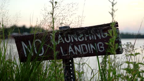 no launching, no landing signboard on the bank of lake at sunset