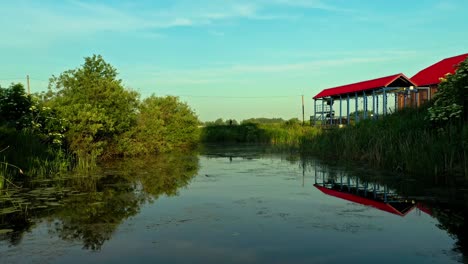 Uncrecognisable-man-walking-on-bridge-above-reflective-lake---Drone-Low-Aerial-Shot