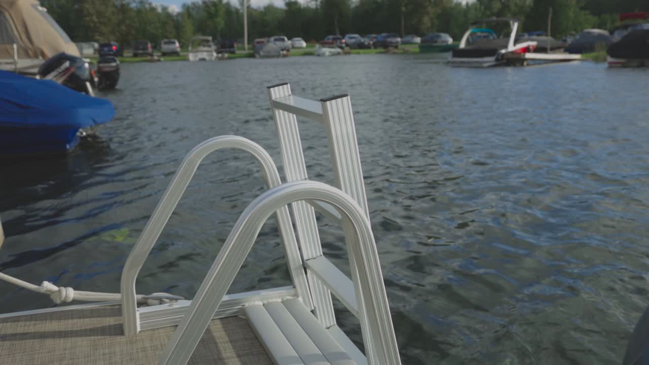 Bootsleiter an einem ruhigen See mit geparkten Fahrzeugen im Hintergrund während des Tages. – Nahaufnahme